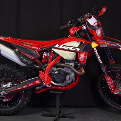 Motocicleta Beta RR 350 vermelha e preta com pneus de cravos e etiquetas de marcas, sobre fundo preto