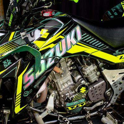Motocross Suzuki preto e amarelo com adesivos e motor metálico