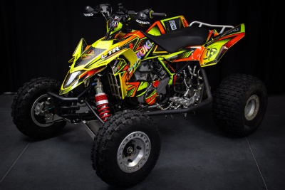 Quadriciclo desportivo amarelo e preto com padrões coloridos e pneus off-road