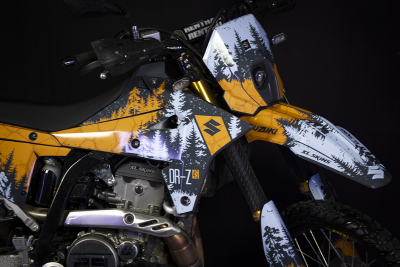 Motociclo Suzuki DR-Z 4S com gráfico laranja, cinzento e branco de árvores e logotipos