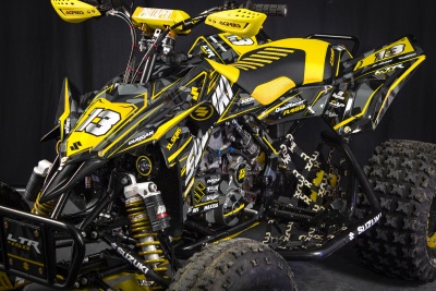 Quad Suzuki LTR 450 preto e amarelo com número 13 e várias marcas em fundo preto