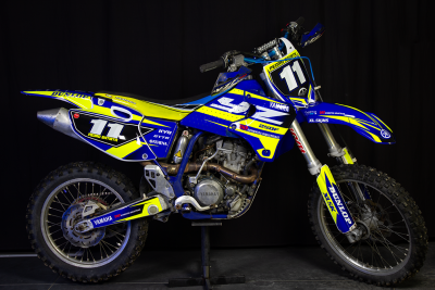 Motocross Yamaha azul e amarelo com número 11 em fundo preto