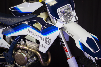 Moto de motocross Husqvarna com carenagens brancas e azuis com texto e farol dianteiro