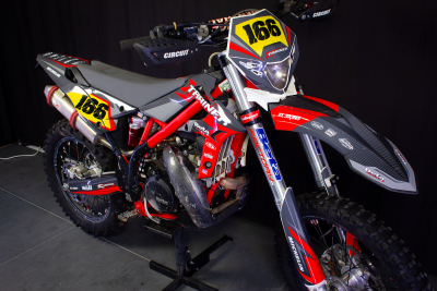 Motocross vermelha e cinza com número 166 em fundo amarelo e vermelho.