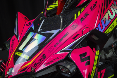 Mota de corrida Suzuki rosa e preta com número 17 e logos de marcas.