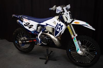 Motocross Husqvarna branca e azul com pneus de cravos e suspensão amarela