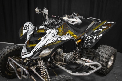 Quad Yamaha branco, preto e amarelo com números, grafismos e pneus grandes