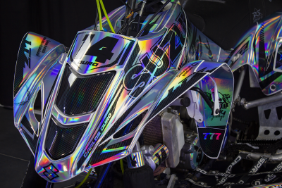 Veículo todo-o-terreno com carenagem holográfica e detalhes pretos com números e texto coloridos.