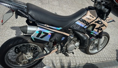 Motocicleta Yamaha DTR 125 preta e bege com assento em pele preta e número 17 holográfico estacionada no exterior