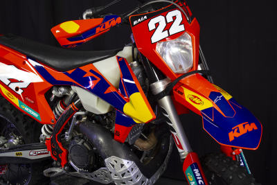 Motocross KTM vermelho, azul e amarelo com número 22 e autocolantes diversos