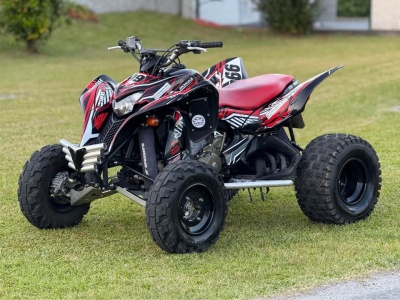 Quadriciclo desportivo preto e vermelho com pneus grandes estacionado em relvado