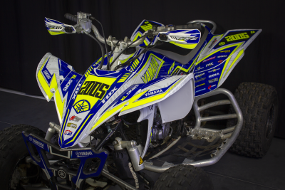 Quad de competição azul, branco e amarelo com adesivos Yamaha e 2005