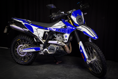 Motociclo Suzuki DR-Z azul e branco em fundo escuro