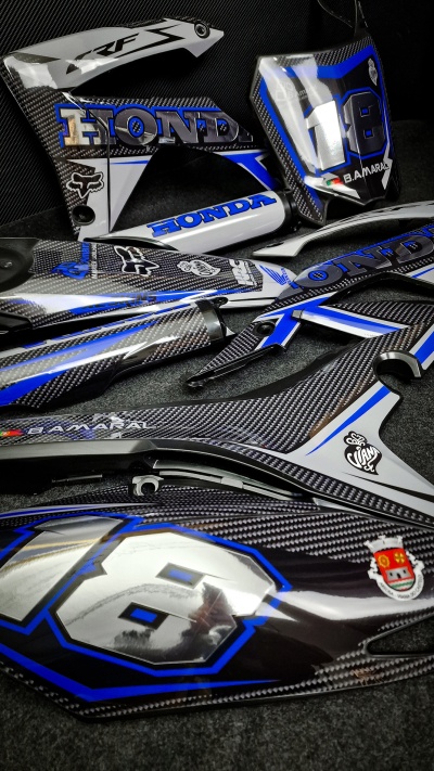 Peças para motocicleta Honda em carbono azul e branco com números e logos.