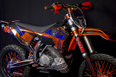 Motocross KTM preto, laranja e azul com pneus todo-o-terreno e guarda-mãos laranja