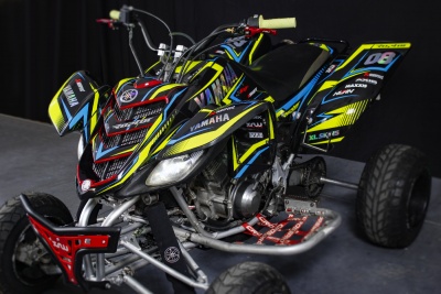 Quadra desportiva Yamaha preta, azul, amarela e vermelha com o número 08 e manípulos amarelos