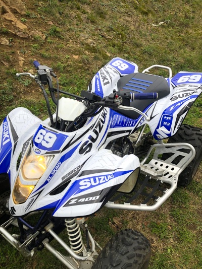 Quad Suzuki Z400 branco e azul com número 69 em área de relva e terra