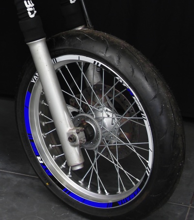 Roda dianteira de mota com jante prateada, riscas azuis, texto YAMAHA e garfo prateado