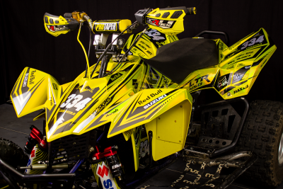 Quad amarelo com número 934 e várias marcas, sobre fundo preto