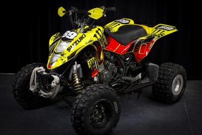 Quad Suzuki amarelo, vermelho e preto em fundo escuro