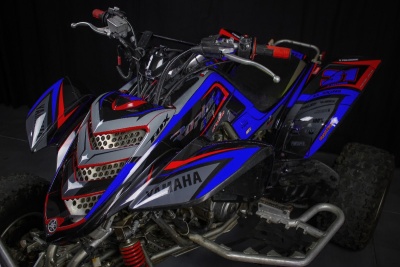 Quad Yamaha azul, vermelho e cinza com número 31 na traseira e pneus com textura de lama