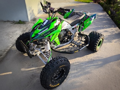 Quadriciclo Kawasaki verde e preto com pneus Maxxis em pavimento