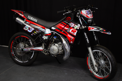 Motocross Yamaha preta e vermelha com número 53 em fundo escuro