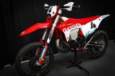 Motocross GASGAS vermelha e branca com número 4 apoiada em suporte.
