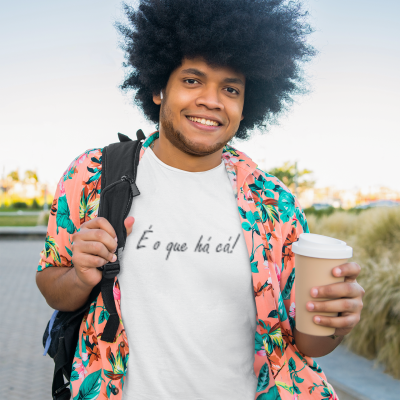 Homem jovem com t-shirt branca com texto e camisa florida cor-de-rosa a segurar um café ao ar livre