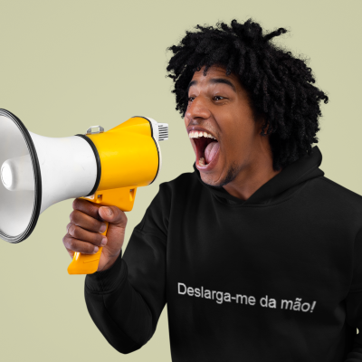 Homem a segurar megafone amarelo e branco, veste casaco preto com texto branco