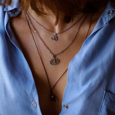Colar duplo com pendentes OM e flor de lótus sobre camisa azul