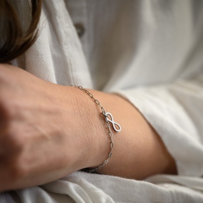 Pulseira de corrente prateada com símbolo do infinito no pulso