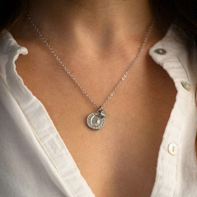 Colar prateado com medalhas redondas e camisa branca