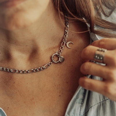 Colar de corrente prateada com pendentes de coração e lua no pescoço