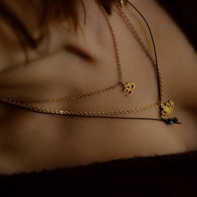 Colares dourados com pendentes Om e folha no pescoço