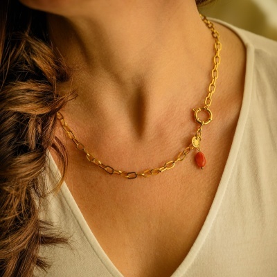 Colar dourado com pendente vermelho e medalha oval ao peito