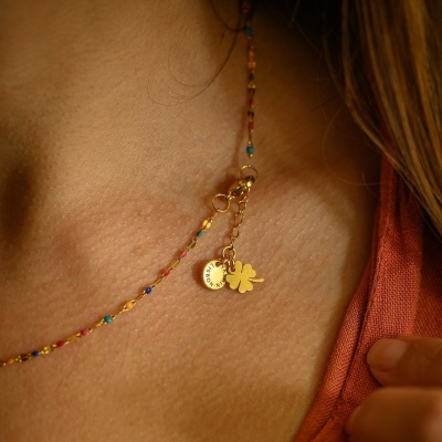 Colar dourado com contas coloridas e pendentes de trevo e disco com inscrição