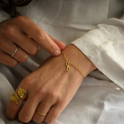 Pulseira dourada com símbolo de infinito no pulso de uma pessoa
