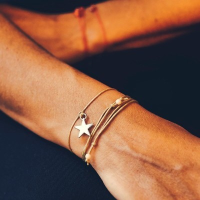 Pulseira fina com pingente de estrela prateada no pulso