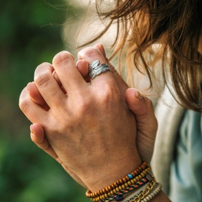 Mãos entrelaçadas com anel prateado e várias pulseiras coloridas