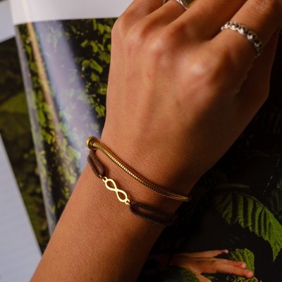 Pulseiras de corda castanha e corrente dourada no pulso