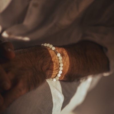 Pulseira branca de contas redondas no pulso de pessoa de pele escura