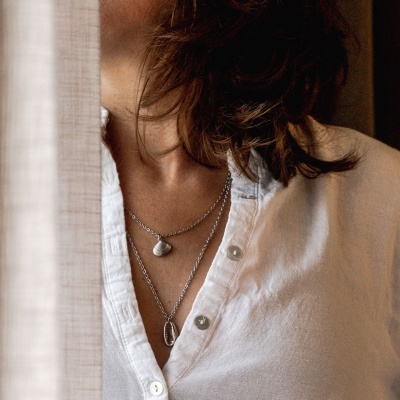 Colar duplo feminino prateado com pendentes de concha em mulher com camisa branca