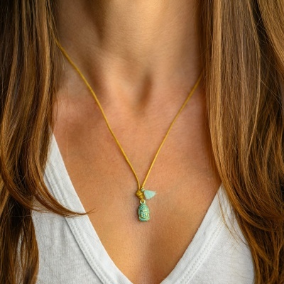 Colar com pendente Buda verde em fio amarelo numa mulher com blusa branca