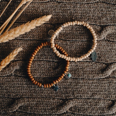 Dois braceletes de contas em madeira sobre tecido castanho trançado