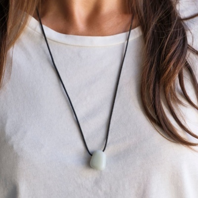 Colar com pendente de pedra branca em cordão preto sobre t-shirt branca