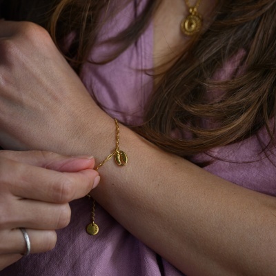 Pulseira dourada com pendentes usada no pulso