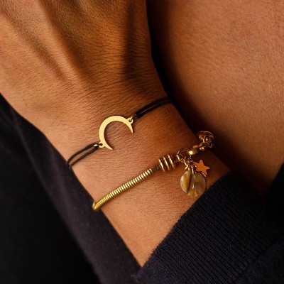 Pulseiras femininas douradas e em cordão preto num pulso