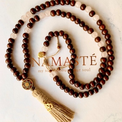 Colar de contas em madeira e pedra com pendente decorativo e tassel sobre fundo branco com texto NAMASTÉ.