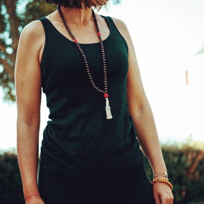 Regata preta de malha canelada usada por mulher com colar de contas e bracelete castanha ao ar livre